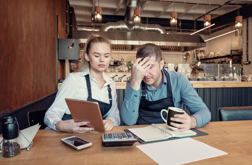 Depressed two entrepreneurs man and woman inside their restaurant overwhelmed by finance problems